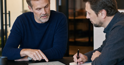 Editorial-style business advisory scene showing Bjorn or a business automation advisor reviewing a workflow with a founder or operations lead.